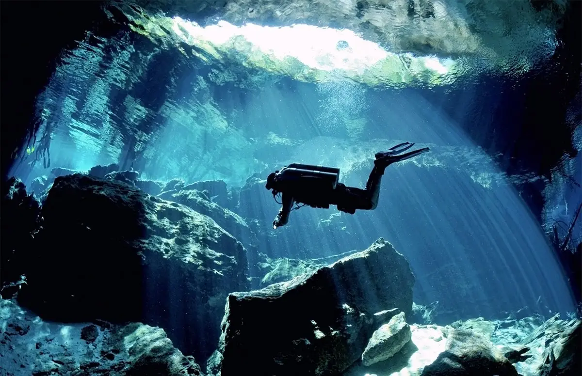 Divers drifting along a rocky underwater reef